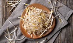 Bean sprouts in a wooden plate set against an old wooden background.