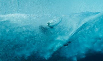 Caroline Marks's hand passes through a blue wave as it breaks over her