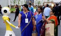 Indian women shake hands with a robot during the Bengaluru Tech Summit 2019 in Bangalore, India
