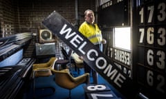 Phillip Costello is behind the scoreboard holding a 'welcome' sign