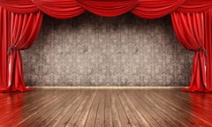 An empty stage framed by a red curtain