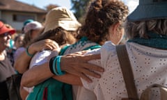 A group of women stand in a line with their arms on each other's shoulders.