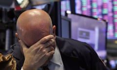 A trader has his head in his hand on the floor of the New York stock exchange