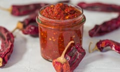 Traditional homemade harissa sauce<br>Traditional homemade Harissa sauce with red chili pepper in glass jar on grey background close up . Moroccan and Arabic cuisine