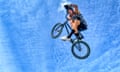Young man performing stunt with bicycle against blue sky