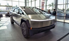 A futuristic looking car sits in a showroom while two people chat in the background