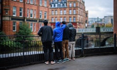 Four young men stand overlooking a river with their backs turned