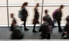 Blurred image of secondary school pupils moving by a window in a school, UK