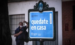 A man waits in front of a poster with a message from the government to ask people to comply with quarantine rules, in Buenos Aires, Argentina.