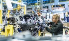 A young female apprentice engineer on the car factory production line.