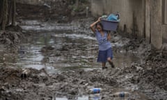 A resident continues to extract items from her home after it was flooded by last year's hurricanes Eta and Iota in the Saviñon Cruz neighborhood of San Pedro Sula, Honduras, Tuesday, Jan. 12, 2021. The devastation wrought by November's hurricanes and the economic damage of the COVID-19 pandemic has added to the forces of poverty and gang violence that drive Hondurans to migrate. (AP Photo/Moises Castillo)