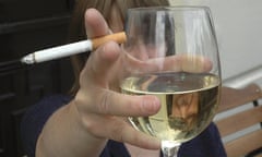 A person holding a cigarette and a glass of wine