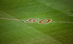 A green grass AFL field with a large red '50' painted on the grass with red lines curving away on either side