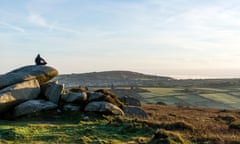 A person meditates on the granite rocks in Carn Brea, Cornwall<br>M0H6NR A person meditates on the granite rocks in Carn Brea, Cornwall