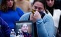 A woman tearfully holds a photograph of a smiling man.