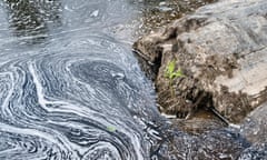 Polluted water swirls by a rock on the River Teifi