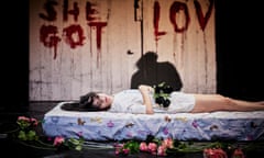 Carolina Bianchi lying on a mattress with flowers around it in Cadela Força Trilogy