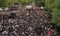 A large crowd tightly packed into a tree-lined street