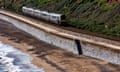 A train travels along a railway line next to the sea wall at Dawlish, Devon.