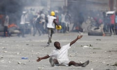 In this Oct. 4, 2019 photo, a protestor drops to the ground as he pleads with police after they fired tear gas to prevent protestors from marching toward the United Nations headquarters in Port-au-Prince, Haiti. Thousands of protesters marched through the Haitian capital to the U.N. headquarters Friday in one of the largest demonstrations in a weeklong push to oust the embattled President Jovenel Moise. (AP Photo/Rebecca Blackwell)