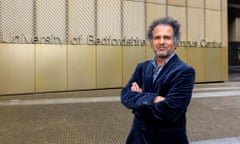 Sarfraz Manzoor in front of a building with sign on it that says 'University of Bedfordshire campus centre'