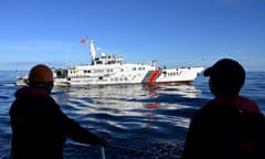 Philippine coast guard personnel look at a China Coast Guard ship during a mission to deliver provisions at Second Thomas Shoal in the South China Sea 