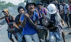 Five young men run with a wounded protester as they seek first aid during a protest against the military coup.