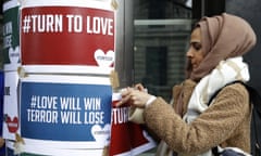 A woman puts up posters from the multi-faith group Turn to Love during a vigil at New Zealand House in London.