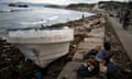 woman eats next to a boat after Hurricane Matthew hit Haiti