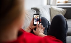 Over the shoulder view of a woman looking at man on an online dating app on her mobile phone