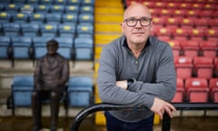 Rochdale chairman Simon Gauge alongside a statue to Rochdale FC superfan David Clough on the seat in the main stand where he had a season ticket for many years.