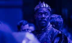 man dressed in costume with a crown photographed in blue-ish light
