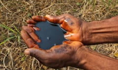 A man holds a pool of black oil in the palm of his hands, collected from oil pollution caused by a damaged pumping station, previously operated by Royal Dutch Shell Plc, near the Ogoniland village of K-Dere, Nigeria, in 2016.