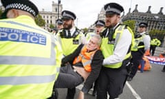 Police officers carry away a man as climate activists from Insulate Britain take part in a demonstration outside the Supreme Court at Parliament Square, London