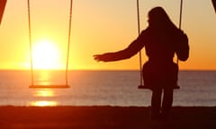 Single or divorced woman alone missing a boyfriend while swinging on the beach at sunset