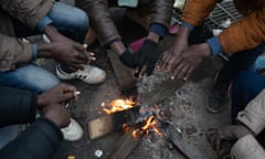 Sudanese migrants warm their hands in a makeshift camp between Calais and Dunkirk, waiting to cross the English Channel via small boats