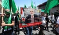 Palestinians hold green flags and carry a placard showing Ismail Haniyeh