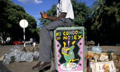 A seller in Bulawayo, the second-largest city in Zimbabwe, sits above a condom awareness poster. 