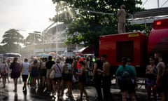 A firefighter cools off Taylor Swift concertgoers with a hose as they queue outside the Nilton Santos Olympic Stadium.