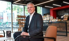 Mike Regnier sits and smiles for the camera in a mordern-style canteen or cafe