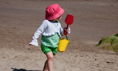 Little girl on the beach wearing a pink hat