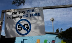 Anti-5G signage at a Telstra exchange facility in Byron Bay with the Telstra transmission tower seen in the background.
