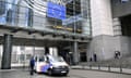 A police officer stands next to a police van outside the EU parliament.