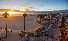 Tourists walking on footpath by beach during sunset. High angle view of Venice beach during sunset.