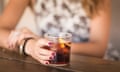 A woman sitting at a table and holding a glass of cola