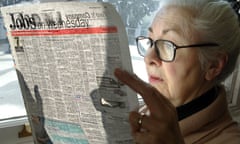 A thoughtful looking woman pensioner surveys the jobs on offer in her local paper.