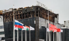 Flags fly at half mast outside a burnt-out concert hall