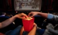 Closeup of a couple at the movies eating popcorn.