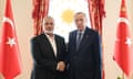 Ismail Haniyeh shakes hands with Recep Tayyip Erdoğan as they both look at the camera with flags on either side of them