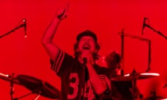 Eddie Vedder, with a long thin moustache and wearing a T-shirt labelled "34" and baseball cap, closes his eyes as he points in the air while singing